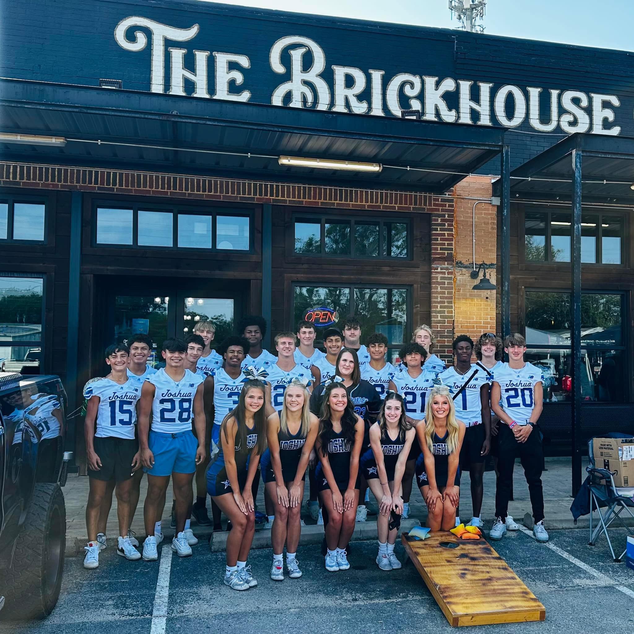 Joshua High School football players and cheerleaders pose together outside The Brickhouse restaurant.