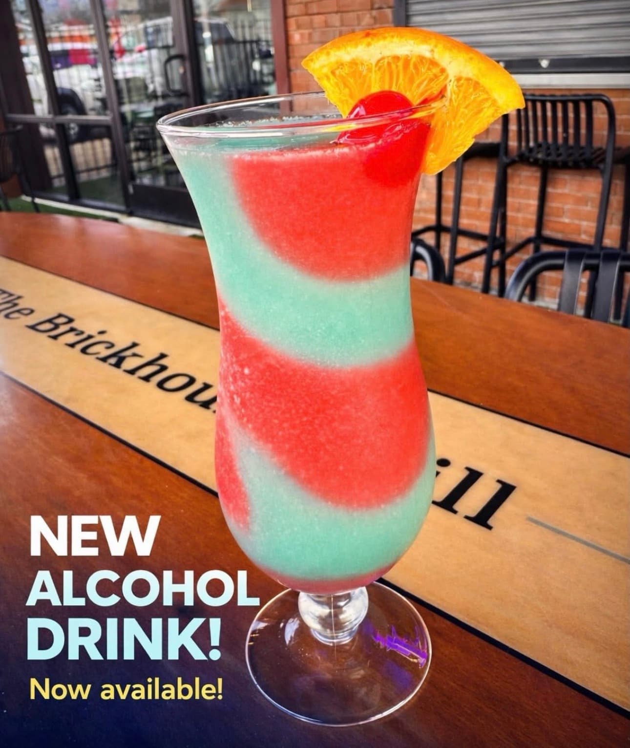 Red and blue swirled frozen cocktail in a hurricane glass garnished with orange and cherry.