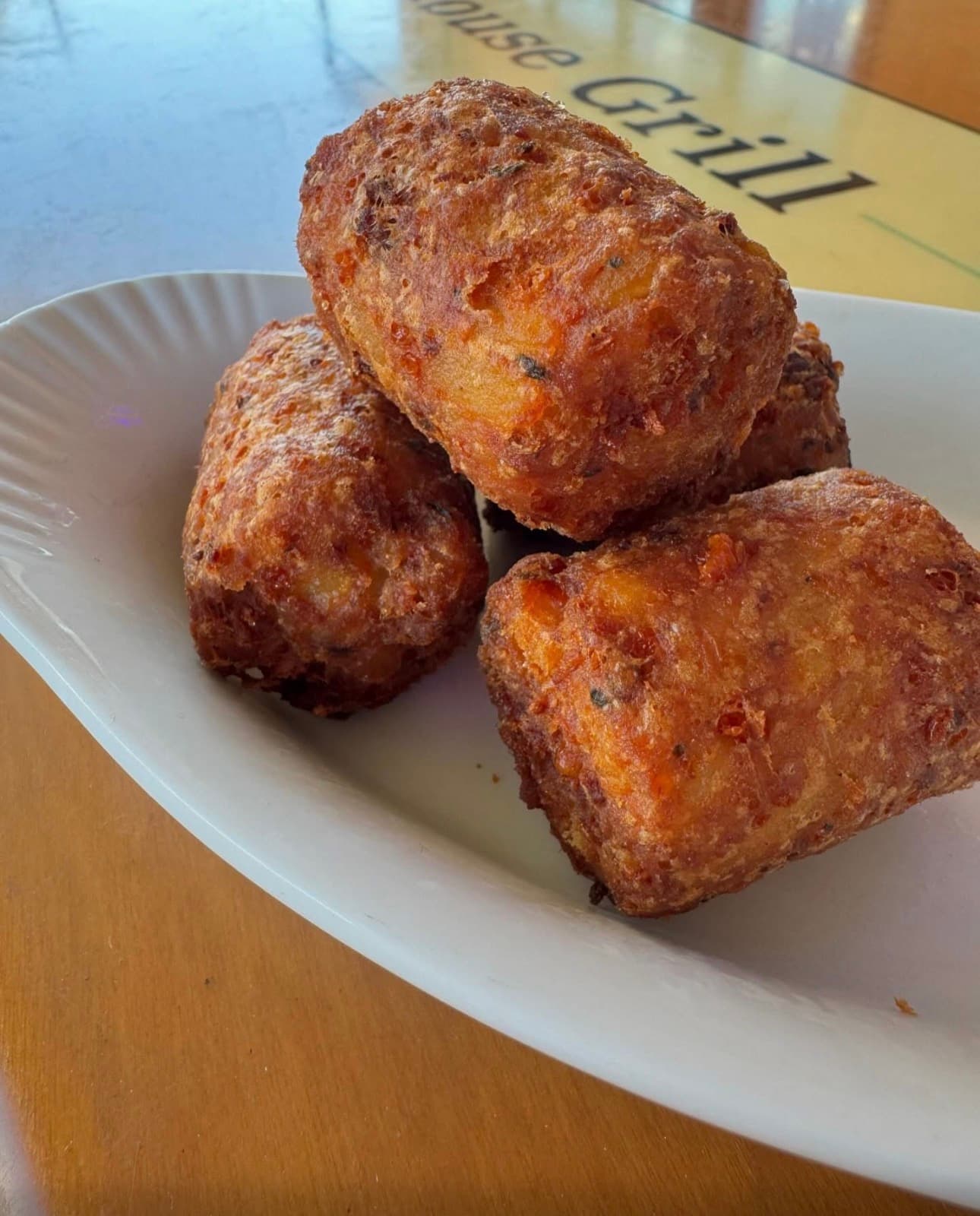 Four large, golden-brown crispy fried potato croquettes stacked on a white plate.